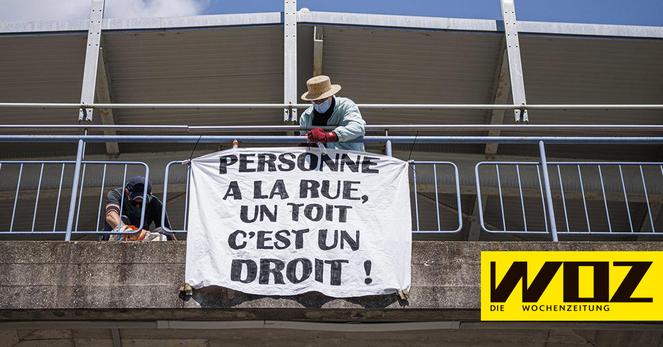 eine Person hängt ein Transparent mit der Aufschrift «PERSONNE A LA RUE, UN TOIT C'EST UN DROIT!» auf