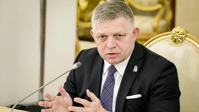 Der Slowakische Premier Fico sitzt vor einem Mikrofon an einem Tisch und gestikuliert.