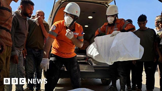 Civil defense teams carry the body of a Palestinian following an Israeli airstrike on residential areas in central Khan Yunis, southern Gaza, on May 23, 2025.