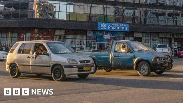 Two cars at a junction on a main road in Zimbabwe. Two cars at a junction on a main road in Zimbabwe.