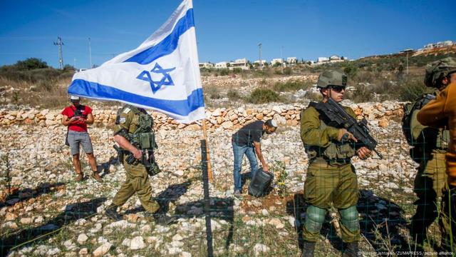 Israeli soldiers guard Jewish settlers as they seize the lands of Palestinian farmers in the village of Burqin, west of Salfit, in the occupied West Bank