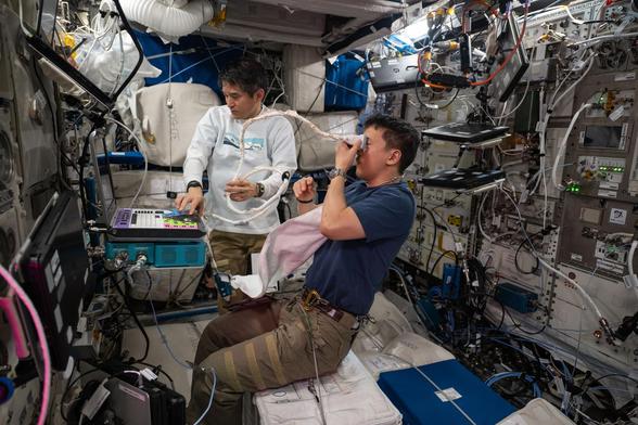 NASA astronaut Jonny Kim, assisted by JAXA astronaut Takuya Onishi, performs an eye ultrasound on the International Space Station.