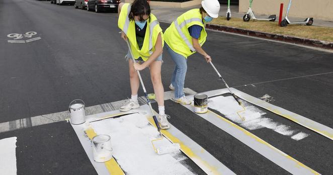 Los Angeles, CA - August 02: Members of Crosswalks Collective LA paint a crosswalk at the intersection of 4th and New Hampshire in Koreatown where Nadir Gavarrete, a 9 year old boy, was killed while riding an e-scooter in a hit and run Thursday night, on Saturday, Aug. 2, 2025 in Los Angeles, CA. (Carlin Stiehl / Los Angeles Times)