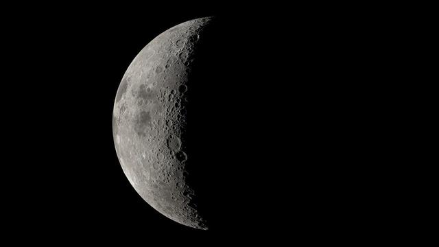 A large sphere is prominent in the center of the image. It is pockmarked with indentations and is generally grey, with patches of dark.
