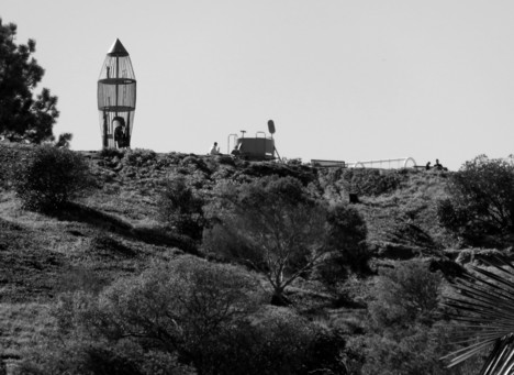 A black and white view of a hillside in the near distance with a rocket-shaped climbing gym.