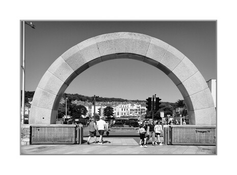 A black and white photograph of a stone block Arch next to a pedestrian crossing - from/to Seafront and from/to a carpark - at Weston-super-Mare, Somerset, UK