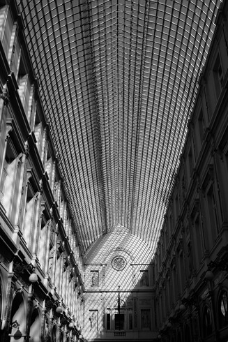 Photo noir & blanc de la galerie du Passage de la Reine à Bruxelles, le soleil passe à travers la galerie du toit, lignes de fuites et diagonales.