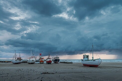 6 Schiffe, die auf dem Sandstrand stehen an der Nordseeküste Dänemarks. Sie werden dorthin gezogen. 