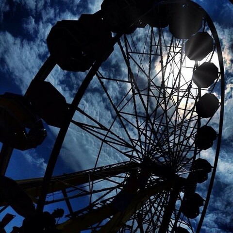 Backlight of ferris wheel making contrast to blue sky