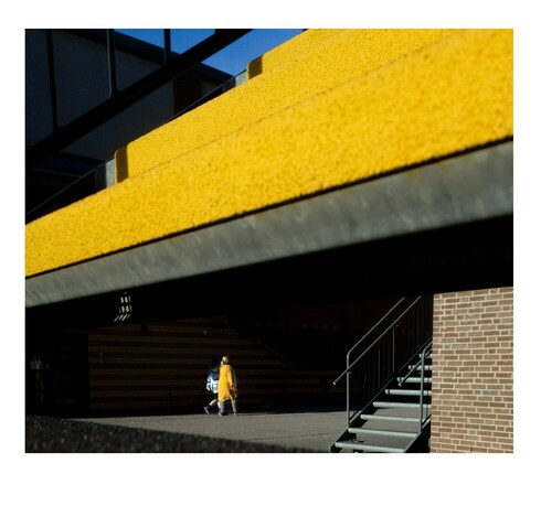 A woman derssed in yellow walking behind yellow stairs