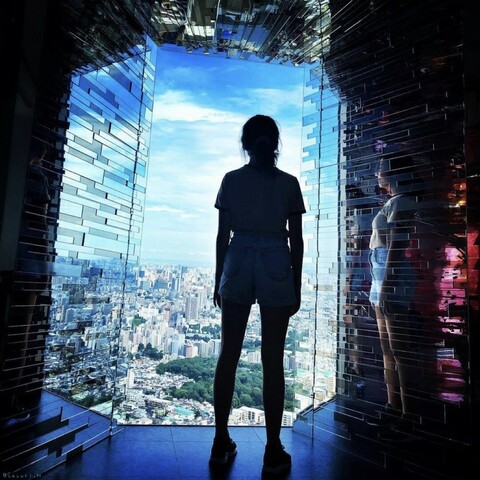 A girl looking outside from the observation deck of high rise building