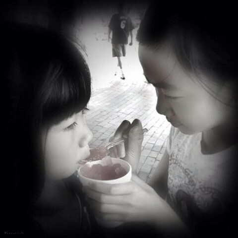 A girl is giving her little sister snow corn by spoon