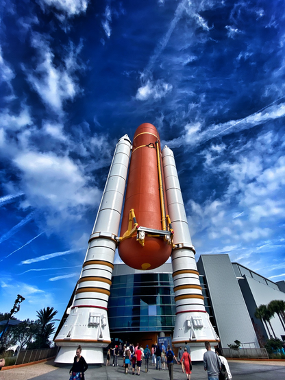 Blue sky, busy clouds, and rocke with boosters