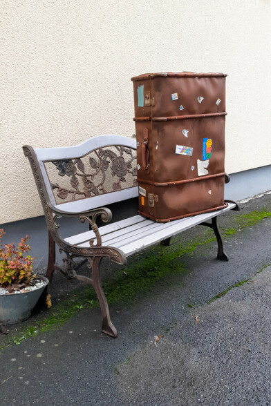 Ein alter Reisekoffer steht auf einer Bank