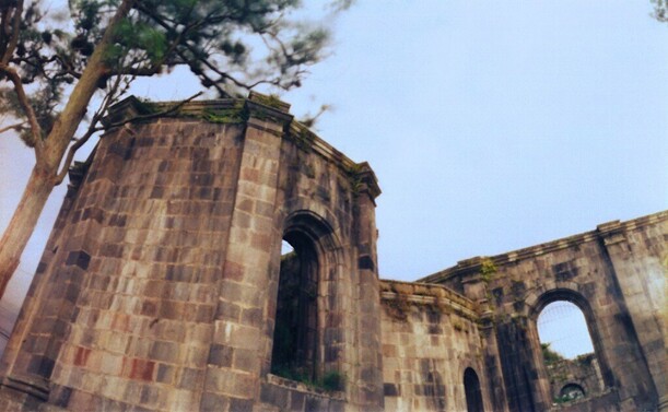 An upward looking view of the ruins of an old church in Costa Rica. A tree hovers above the ruin to the left of the image.