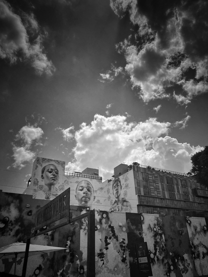 Three faces drawn on the top walls of the buildings.  Front wall along the street is also painted in different patterns. 