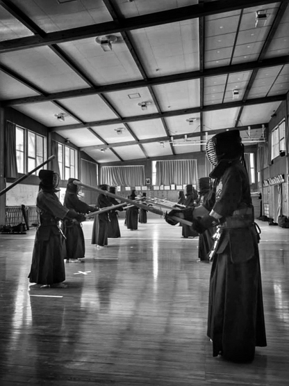 People wearing kendo uniform, protectors, and masks are holding bamboo swords and facing each other for practice 
