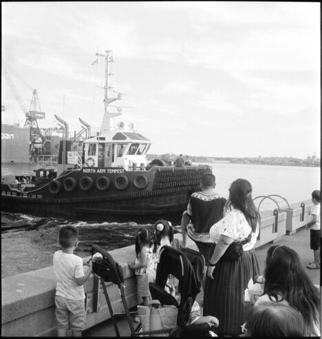 A family watches a tugboat maneuver away from the pier.