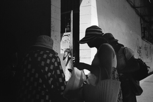 Shoppers explore produce under the shade of an awning.