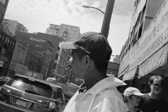 Butcher takes a smoke break. Pedestrians flow by.