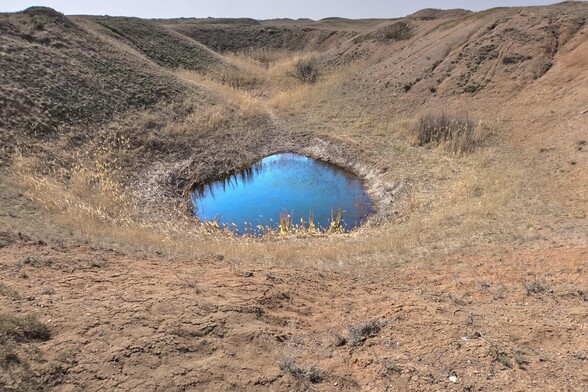 A small blue lake sits at the bottom of a large crater