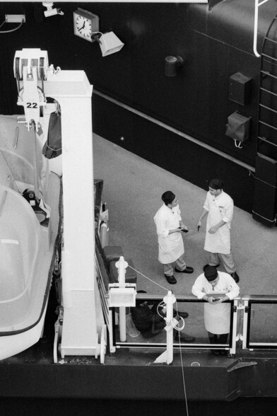 Crew on a cruise ship pass time talking and looking at their phones.
