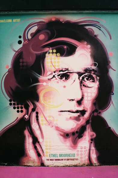 Another portrait colour photograph of the portrait mural of Suffragette Ethel Moorhead. Ethel is shown wearing narrow spectacles that would have been worn in the early 1900s and she is looking to the side.