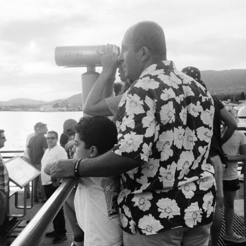 A father and family use a scope to view the city skyline.