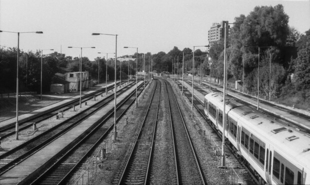 A grainy black and white image of train tracks leading into a station