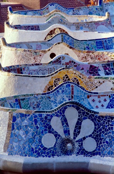 Vertical image of tiles covered benches at Parc Güell in Barcelona, Spain. The photo has been taken with a telephoto lens and along the ax of the swinging line of the benches.