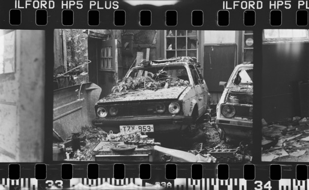 black and white photo of a car in an abandoned building