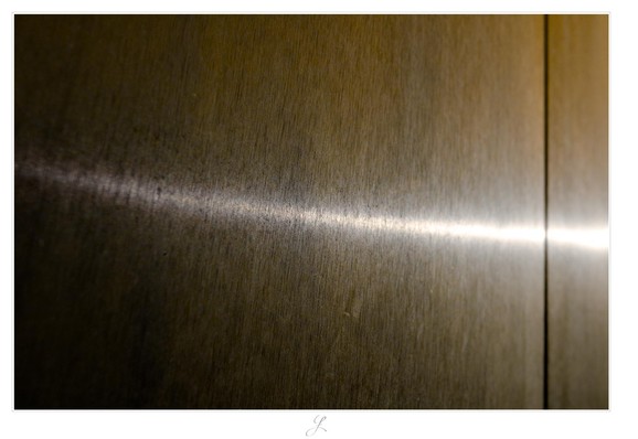 A metal gate made of copper, whose finely textured surface reflects the sun that is shining from the right. The reflection is very bright and broad on the right-hand side of the image and becomes narrower the further it extends in a soft arc to the left. There is a narrow gap between two metal parts of the gate, which extends vertically as a black line in the right-hand part of the picture.

AI disclaimer: Using my work, its meta data, written or derived description to create media with or train AI based systems is prohibited.