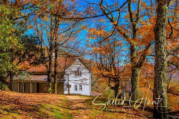 The Moses Cone Carriage House on the Moses Cone Estate near Blowing Rock, North Carolina is showcased in full autumn colors with red and gold leaves and a deep blue sky only seen in Autumn. The estate is located on the Blue Ridge Parkway.  From the Fine Art Gallery of Shelia Hunt.