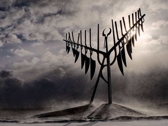 Spirit Catcher, a sculpture in Barrie Ontario by Ron Baird, against a lowering winter sky with the sun behind it.