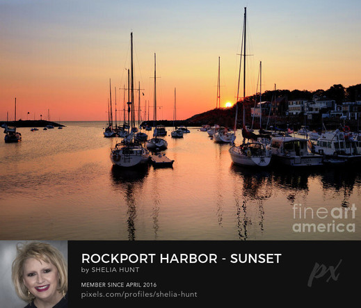 A tranquil scene at Rockport Harbor, Massachusetts is captured at sunset, with the sky painted in warm hues and reflected in the calm water. Sailboats are moored near the dock. From the Fine Art Gallery of Shelia Hunt at Shelia-hunt.pixels.com