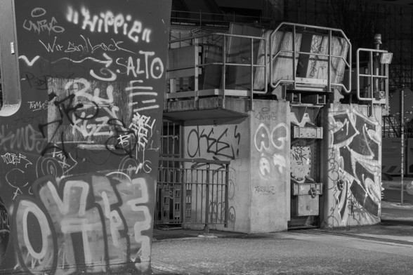 B&W-Bild von Graffiti unterhalb einer Eisenbahnbrücke in Hamburg.

