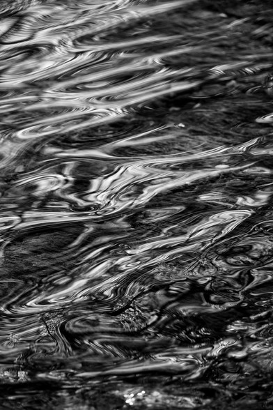 Black and white photo of rippling water with light reflections.