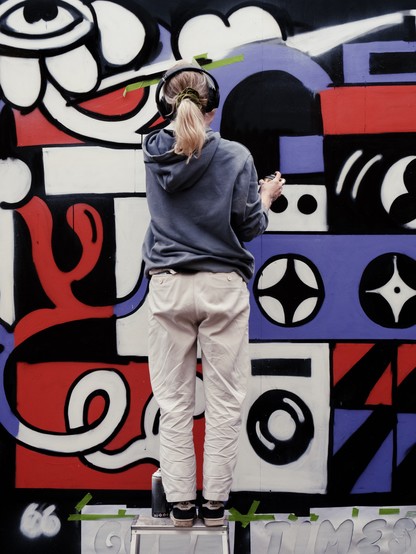 Person painting a colorful graffiti mural.
