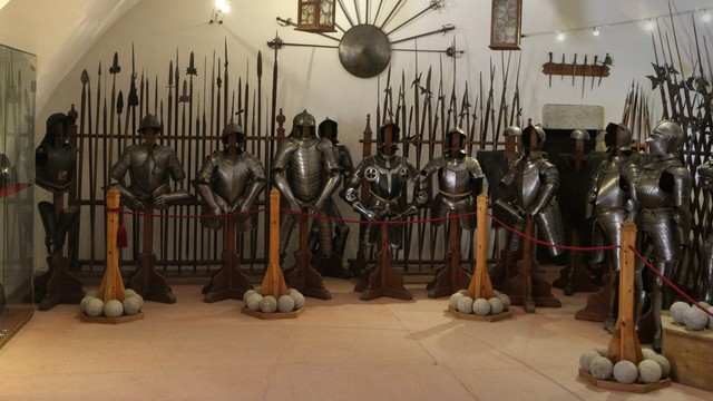 Ein Gewölbe in einem Museum zeigt eine Ausstellung von stählernen Rüstungen und Speere hinter einer Absperrung.