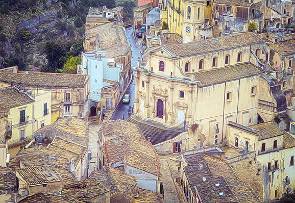 Artistic photography showing a jumble of historic buildings including a church in the center as one looks down on the town of Ragusa, Sicily. 