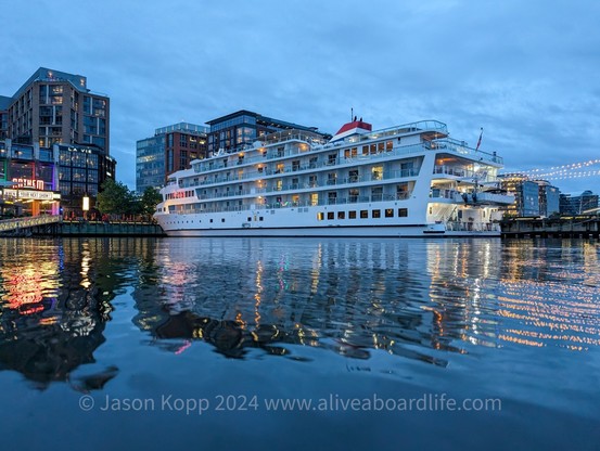 Local cruise ship and wharf buildings and anthem marquee reflecting in water