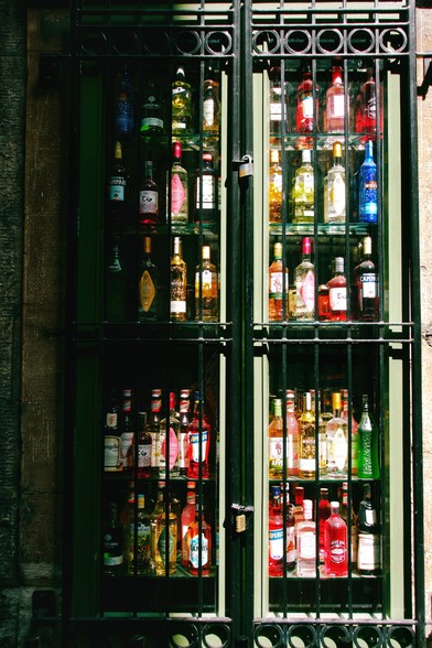 Bottles of spirits displayed behind a window with wrought-iron bars.