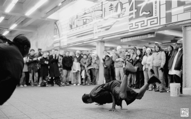 Breakdancers are watche dby public in a subway station (?) in New York City. Impressive performance.