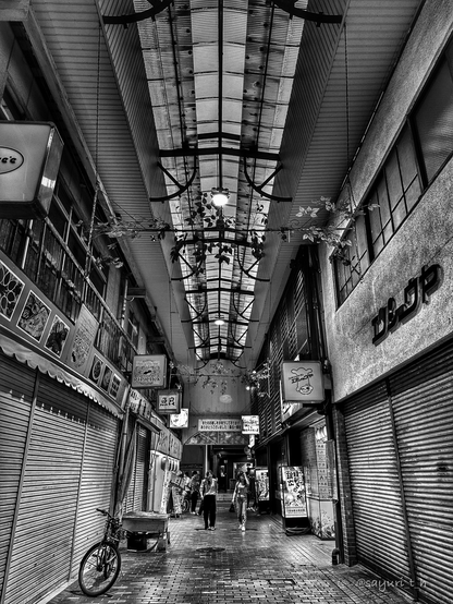 Narrow street under the roof. There are shops and restaurants on both sides of the street and all are closed and shuttered.