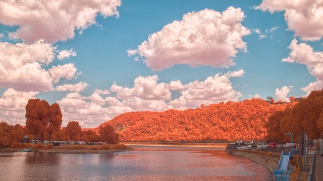 Falschfarben-Foto: unten die Mosel in natürlichen Farben, dahinter ein schmaler Streifen vom Rhein. Links und rechts Bäume und bewachsene Hügel mit Orangefarbenem Laub. Oben ein türkiser Himmel mit weißen Wolken.