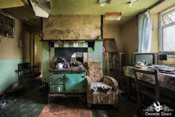 photo of abandoned kitchen, there is a green stove and old chair next to it