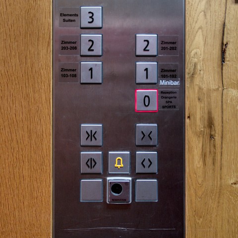 Steuertafel eines Aufzugs mit zwei Türen. Knöpfe für die Etagen 3, 2, 1 und 0, wobei ein Aufkleber 