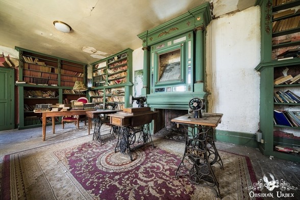 ornate old room with books on the green shelves, desk with red chair, and three vintage sewing machine on tables