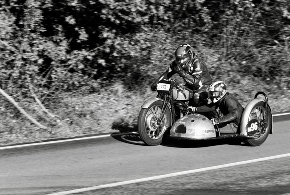 Black and white photo of the vintage motorcycle with sidecar. The riders are relaxed because they are returning to the base after uphill race 