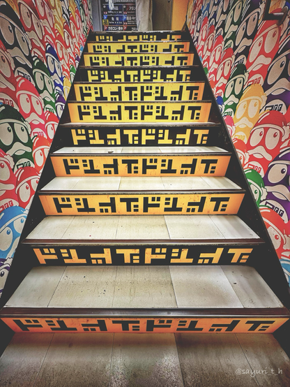 Vertical side of each stair is painted black and yellow with letter s of Do in Japanese written. Side walls are covered with penguins in different colors.
